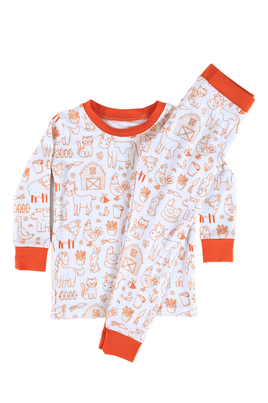 Our two-piece Barnyard Buddies jammies are a charming farm-inspired design featuring a variety of animals including cows, chickens, horses, dogs, cats and more across a white background with matching orange cuffs and trim.