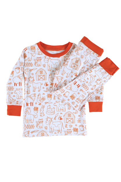 Our two-piece Barnyard Buddies jammies are a charming farm-inspired design featuring a variety of animals including cows, chickens, horses, dogs, cats and more across a white background with matching orange cuffs and trim.